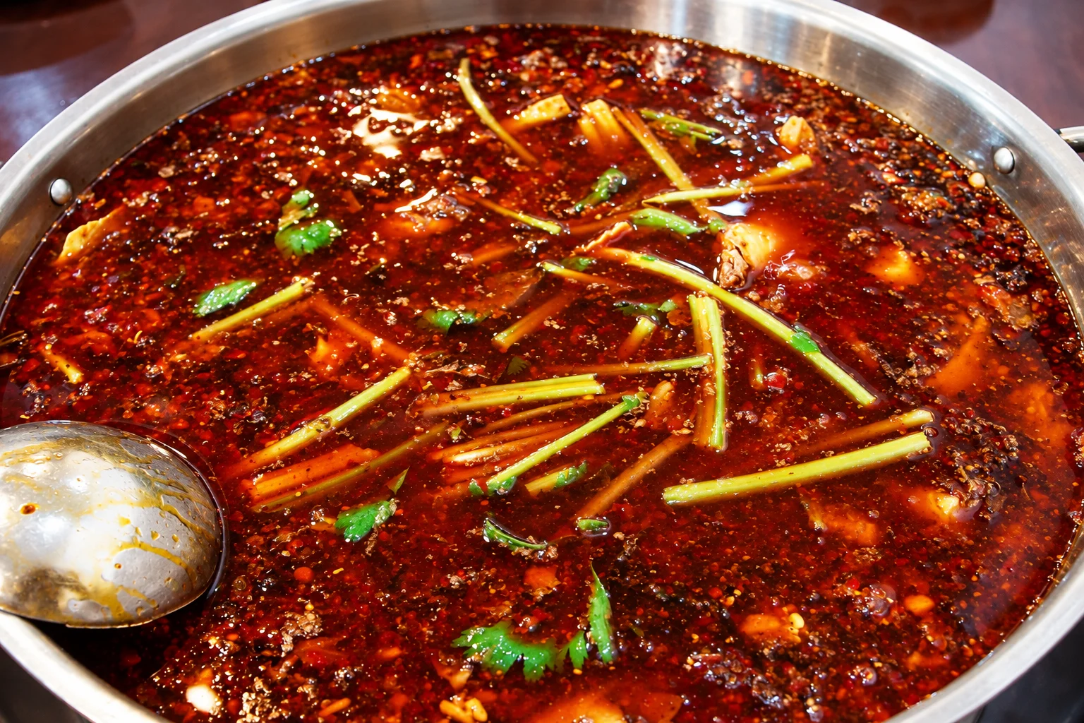 Chongqing hotpot with chili broth and a stainless-steel ladle
